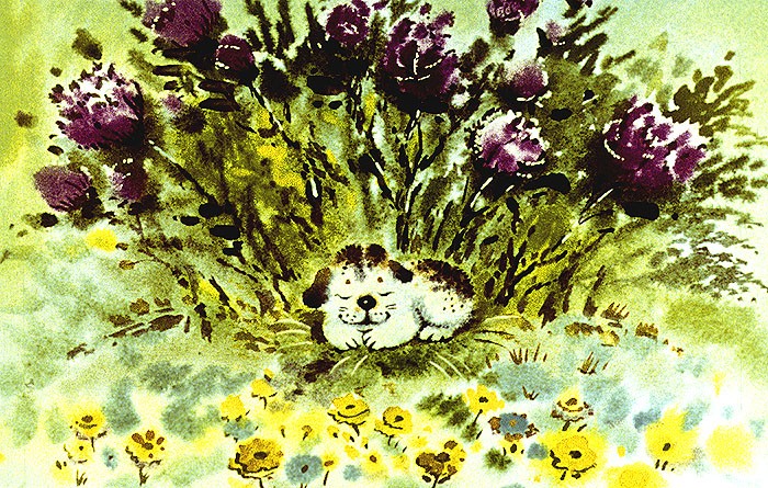 Щенок лежит в клумбе с цветами